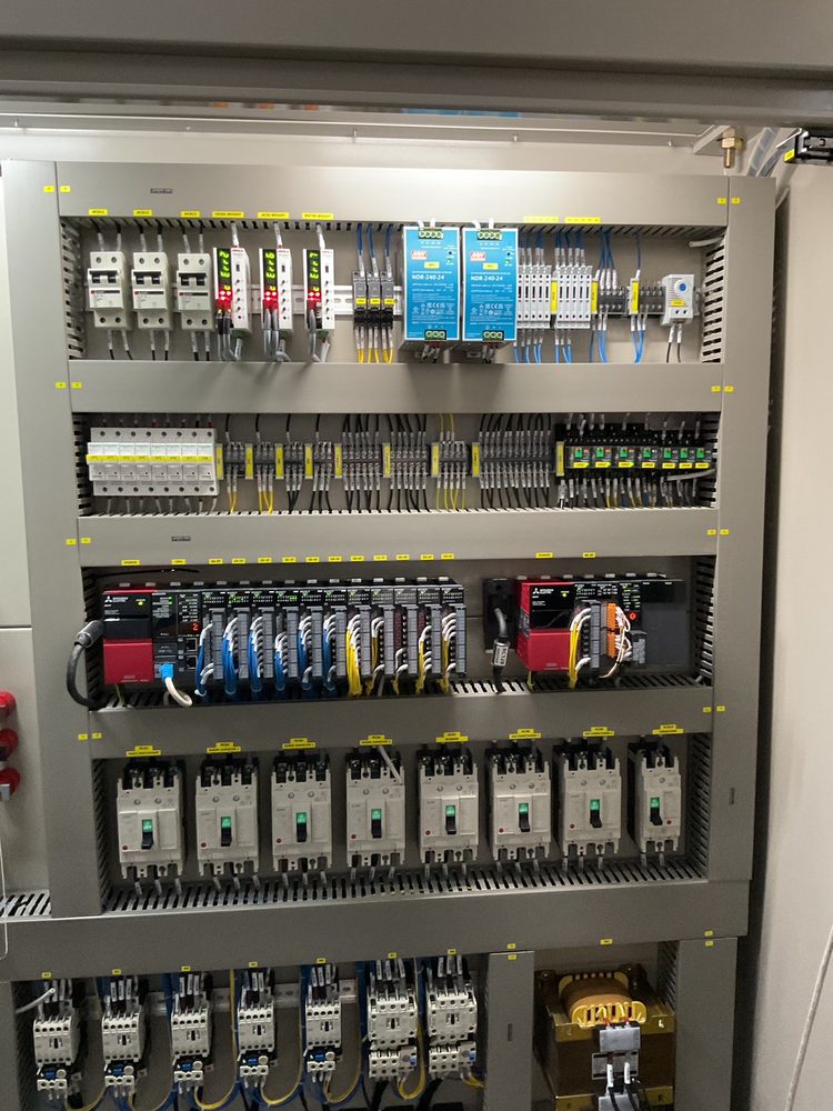 Inside the control panel: breakers, power supplies, controller modules and contactors arranged in functional tiers